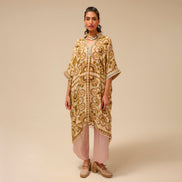 Woman wearing a patterned beige and gold dress on a beige background