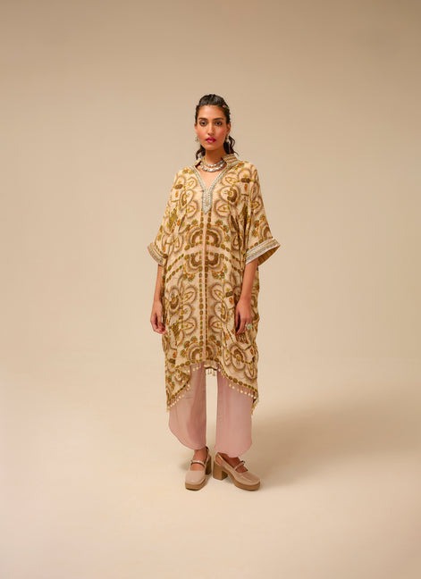 Woman wearing a patterned beige and gold dress on a beige background