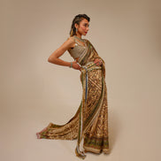 Woman wearing a traditional saree with intricate patterns on a beige background