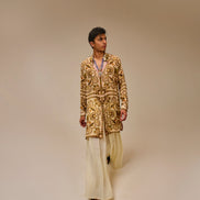 Man wearing a patterned jacket and light-colored pants on a beige background