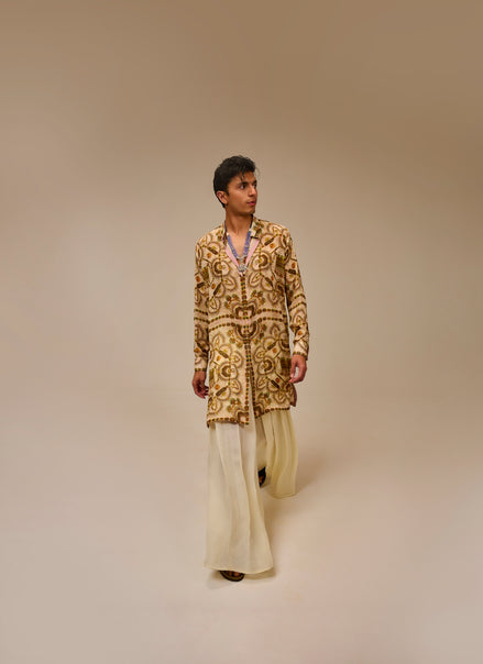 Man wearing a patterned jacket and light-colored pants on a beige background