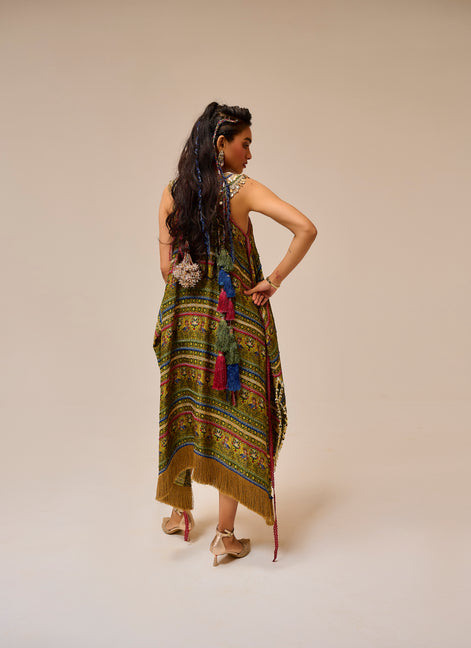 Woman wearing a colorful patterned dress with fringe on a beige background