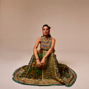 Woman in a colorful traditional outfit sitting on a beige background