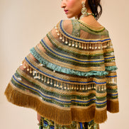 Woman wearing a colorful, patterned shawl with fringe details on a beige background