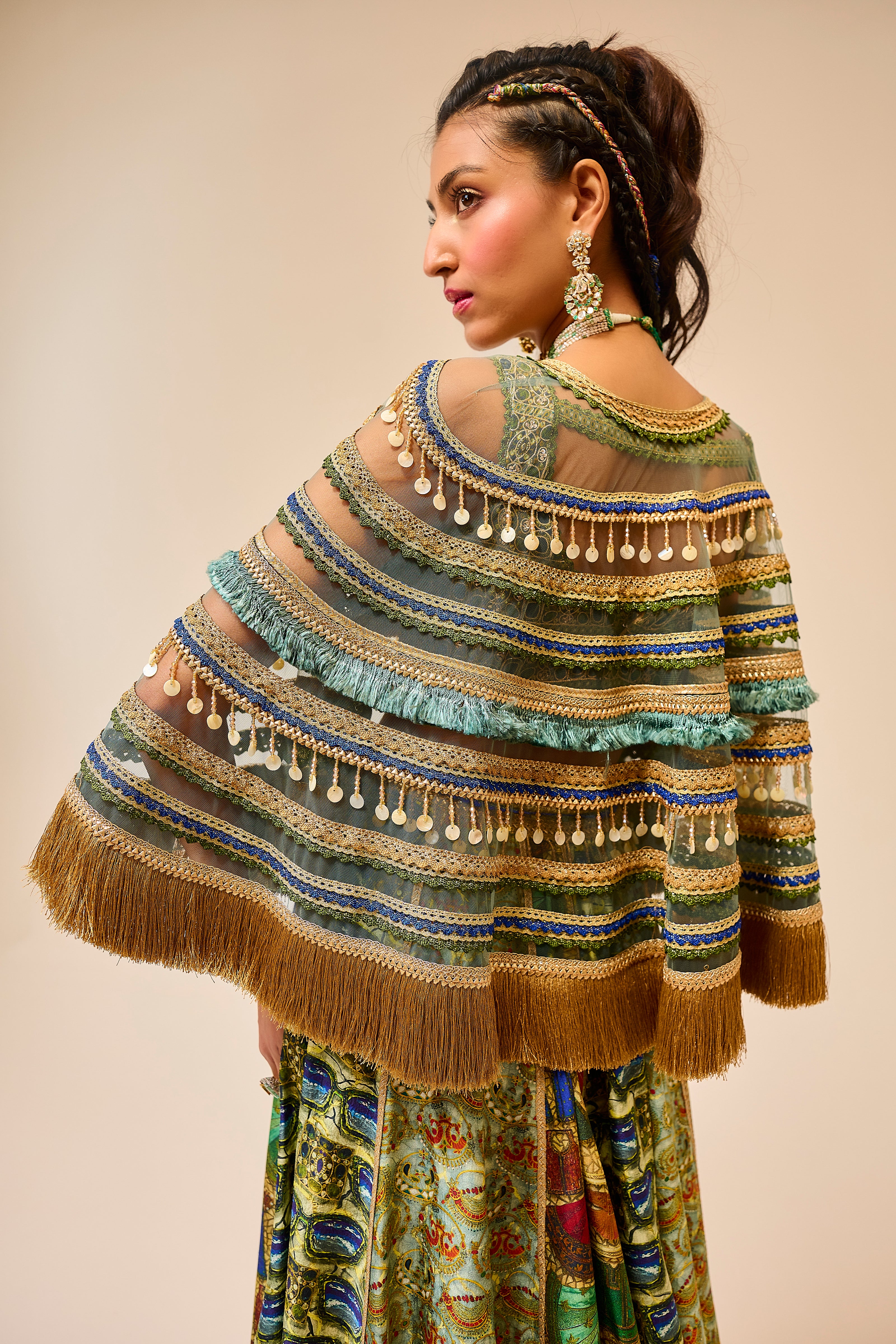 Woman wearing a colorful, patterned shawl with fringe details on a beige background