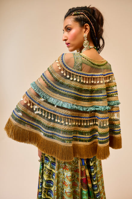 Woman wearing a colorful, patterned shawl with fringe details on a beige background