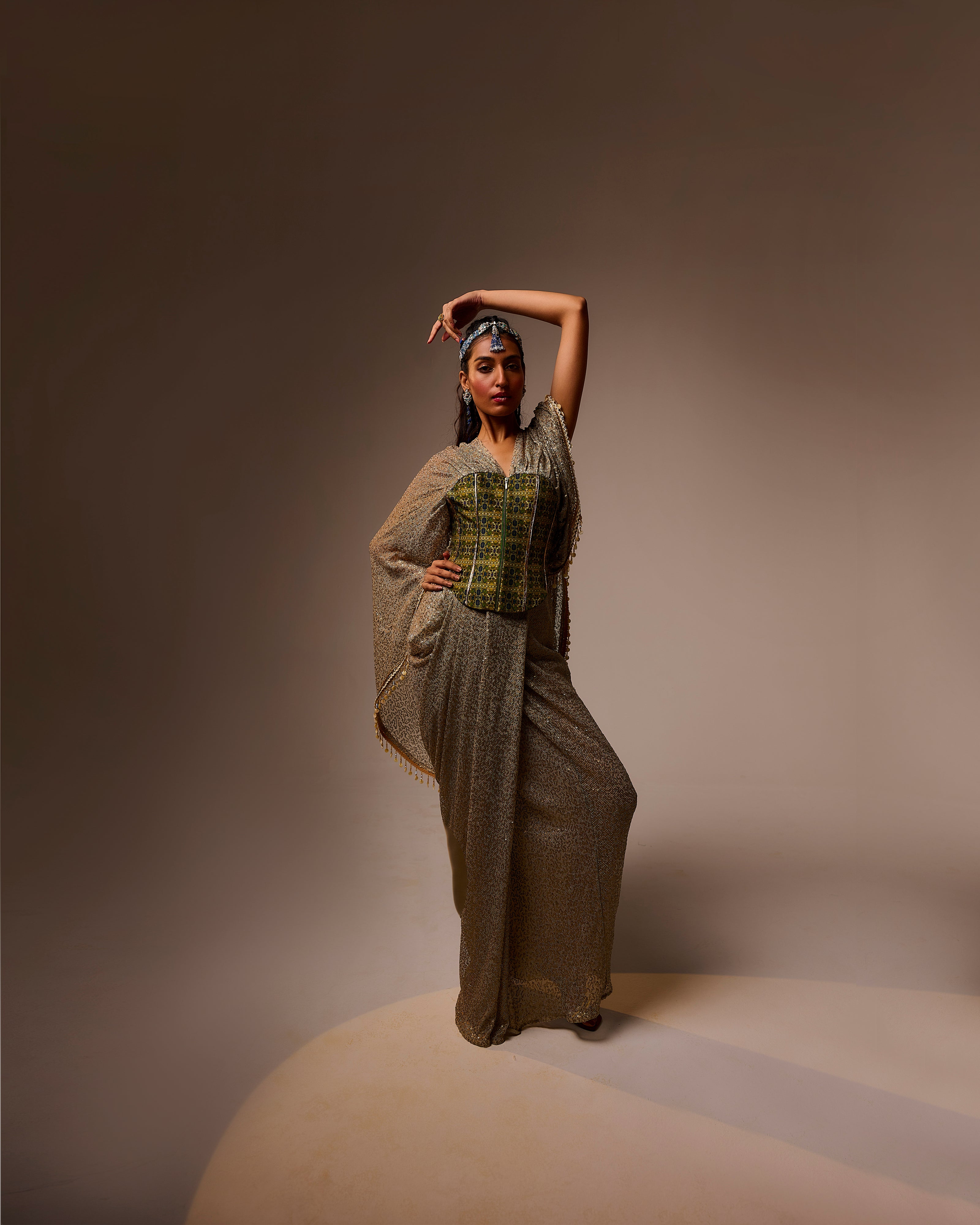 Woman in a long, textured dress with a patterned top against a brown background