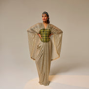 Woman wearing a gold and green traditional outfit on a beige background