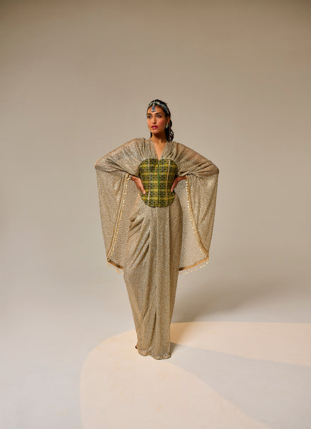 Woman wearing a gold and green traditional outfit on a beige background
