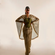 Model wearing a stylish outfit with a cape and patterned top on a plain background