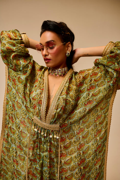 Woman wearing a traditional outfit with intricate patterns and jewelry against a beige background