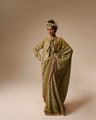 Woman wearing a traditional outfit with a patterned dress and headscarf on a beige background