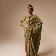 Woman wearing a traditional outfit with a patterned dress and headscarf on a beige background