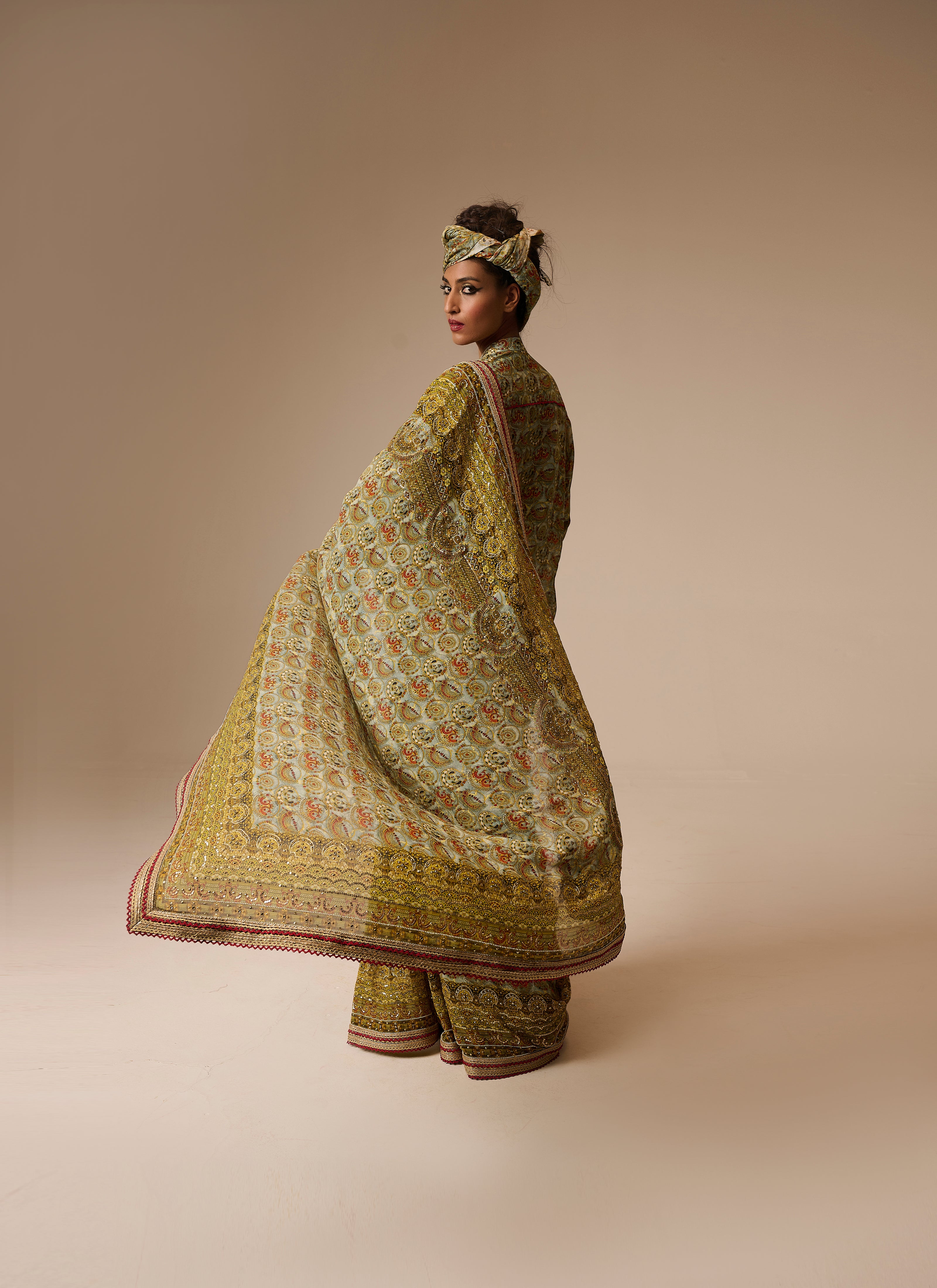 Woman wearing a traditional outfit with a patterned shawl on a beige background