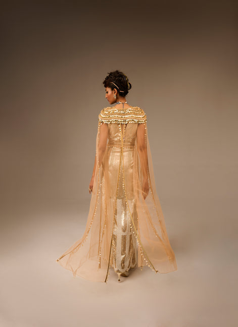 Woman wearing a beige embroidered outfit against a plain background