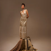 Woman wearing a long, elegant dress with a textured pattern on a brown background