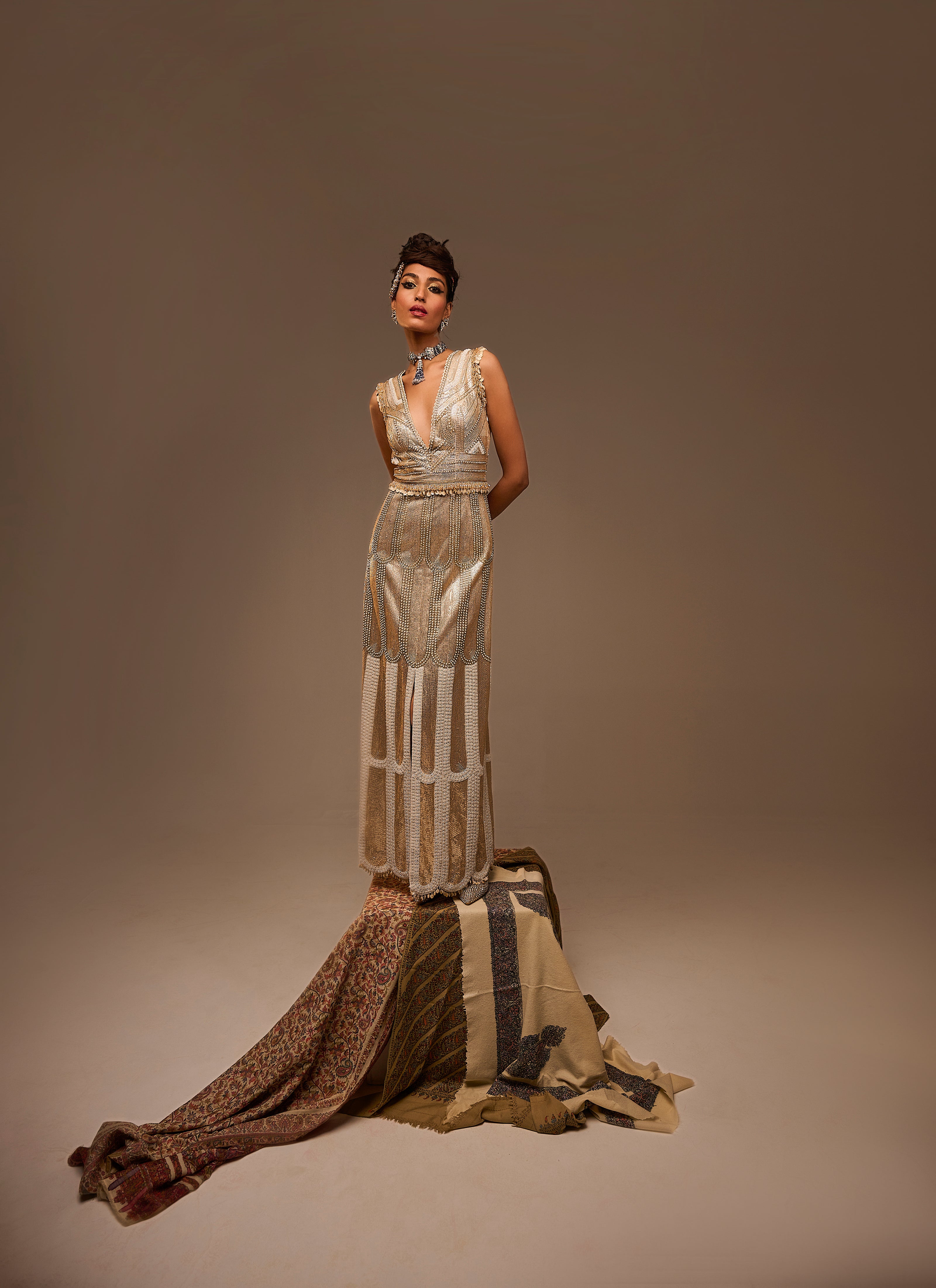 Woman wearing a long, elegant dress with a textured pattern on a brown background