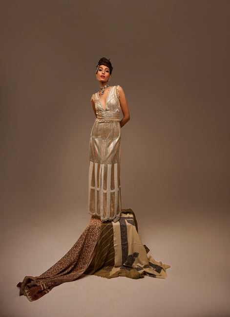 Woman wearing a long, elegant dress with a textured pattern on a brown background