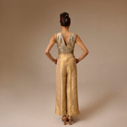 Woman wearing a gold jumpsuit with a plain background