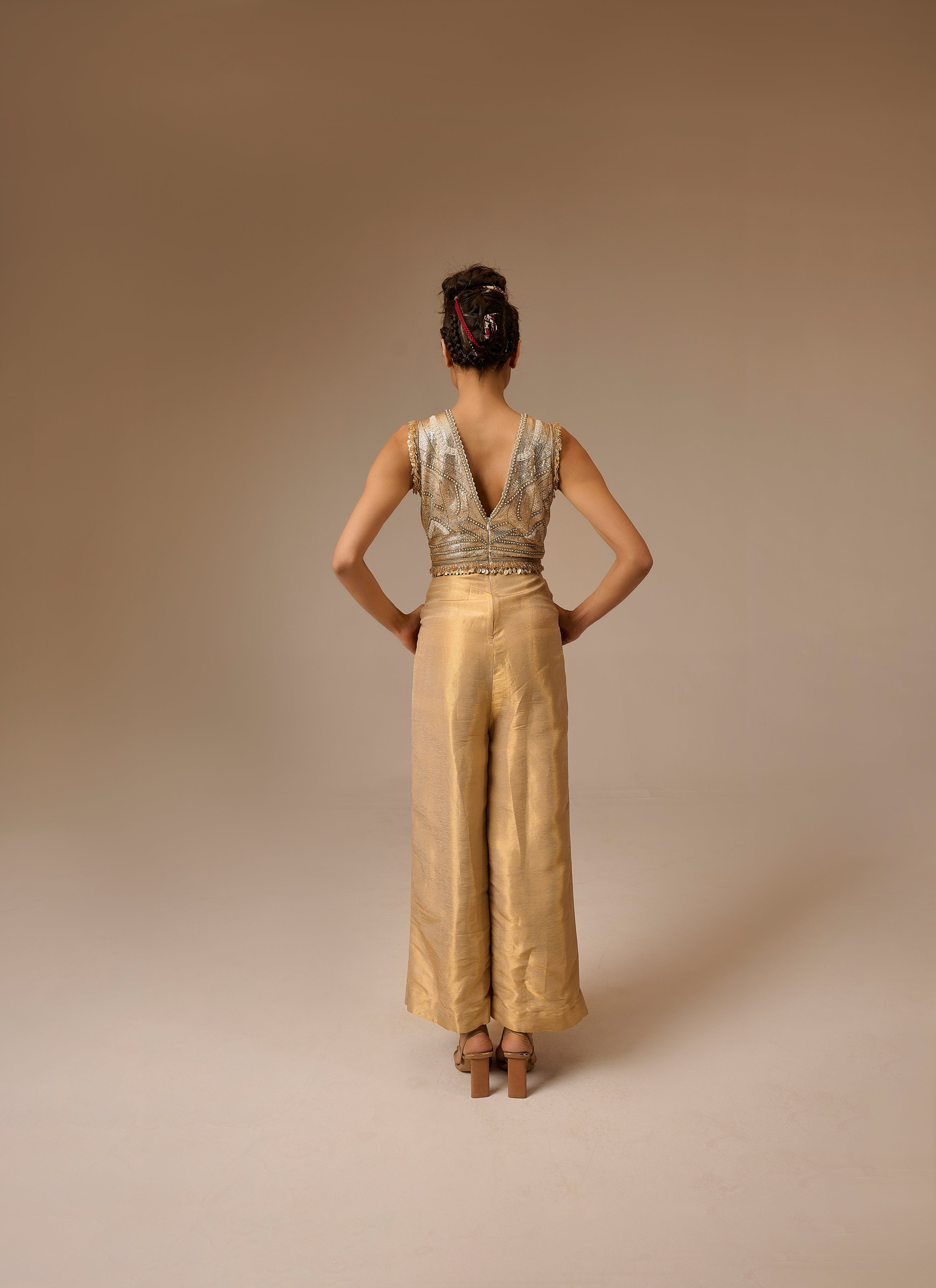 Woman wearing a gold jumpsuit with a plain background