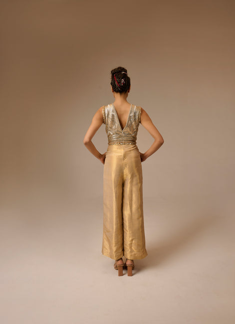 Woman wearing a gold jumpsuit with a plain background