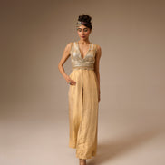 Woman wearing a gold jumpsuit with a plain background