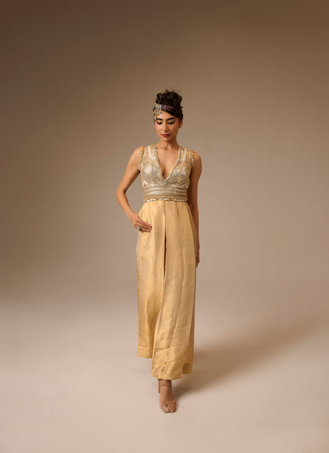 Woman wearing a gold jumpsuit with a plain background