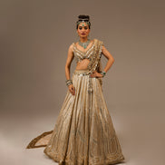 Woman in an ornate traditional outfit with jewelry on a plain background