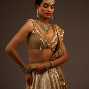 Woman in a gold traditional outfit with jewelry against a dark background