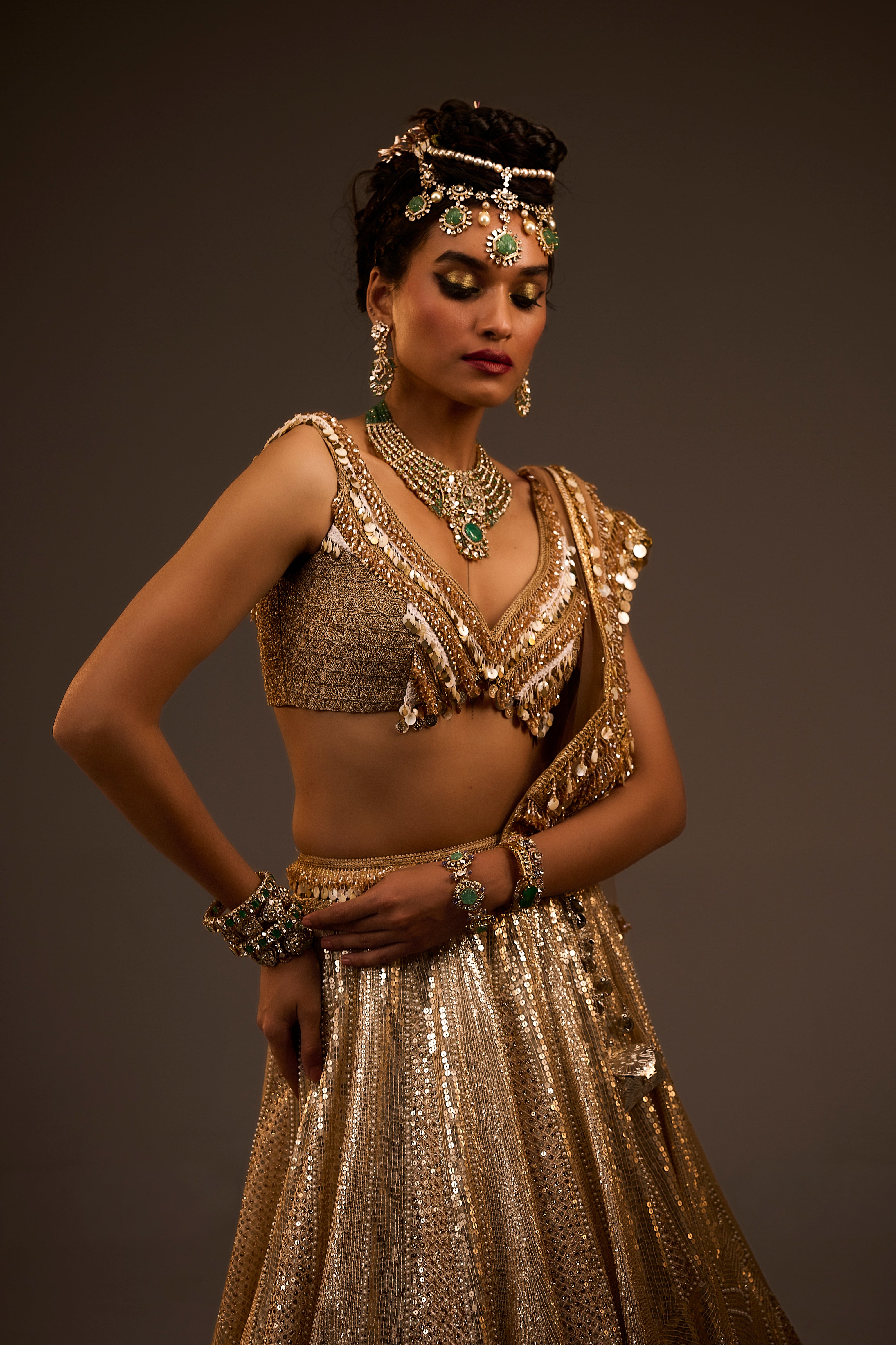 Woman in a gold traditional outfit with jewelry against a dark background