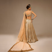 Woman in a traditional beige and gold outfit with a plain background