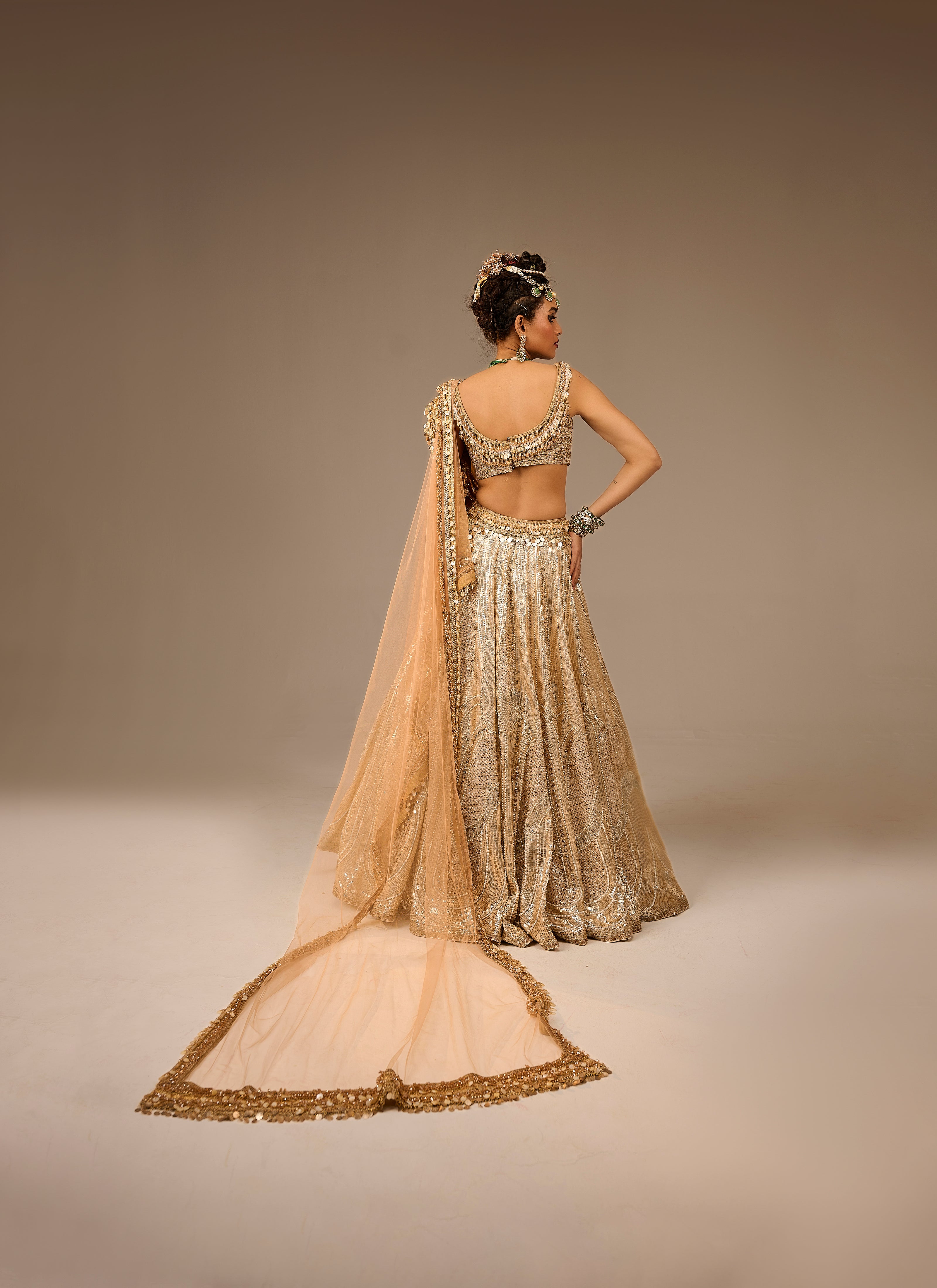 Woman in a traditional beige and gold outfit with a plain background