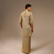 Person wearing a beige traditional outfit on a plain background