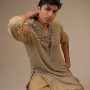 Man wearing traditional attire with a necklace against a beige background