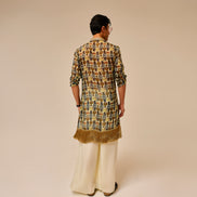 Person wearing a patterned kurta with fringes on a beige background