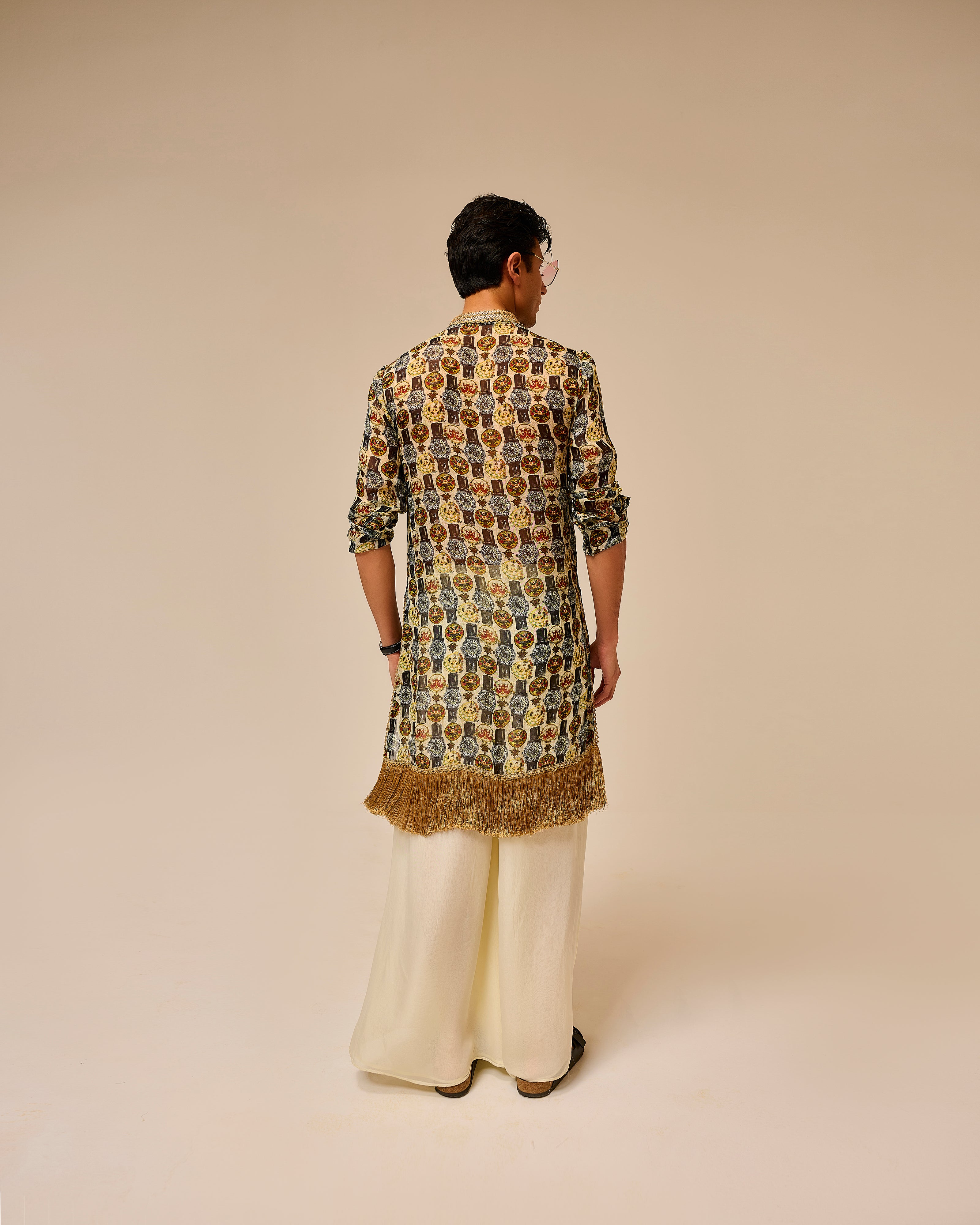 Person wearing a patterned kurta with fringes on a beige background