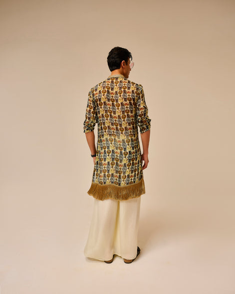 Person wearing a patterned kurta with fringes on a beige background