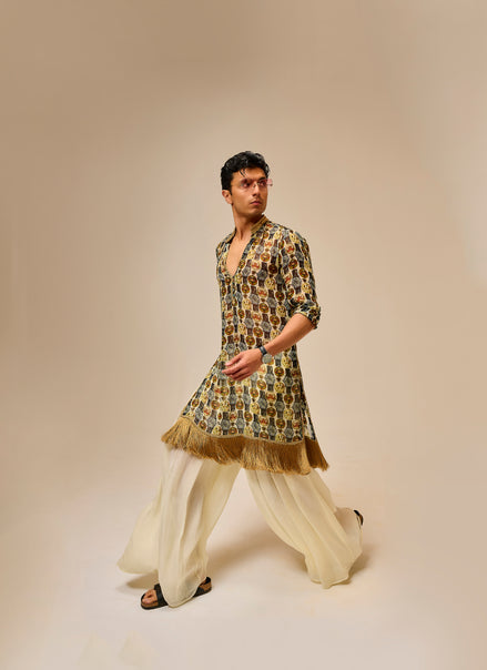 Man wearing a patterned kurta with white pants on a beige background