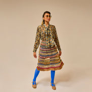 Woman wearing a patterned dress with a colorful skirt on a beige background